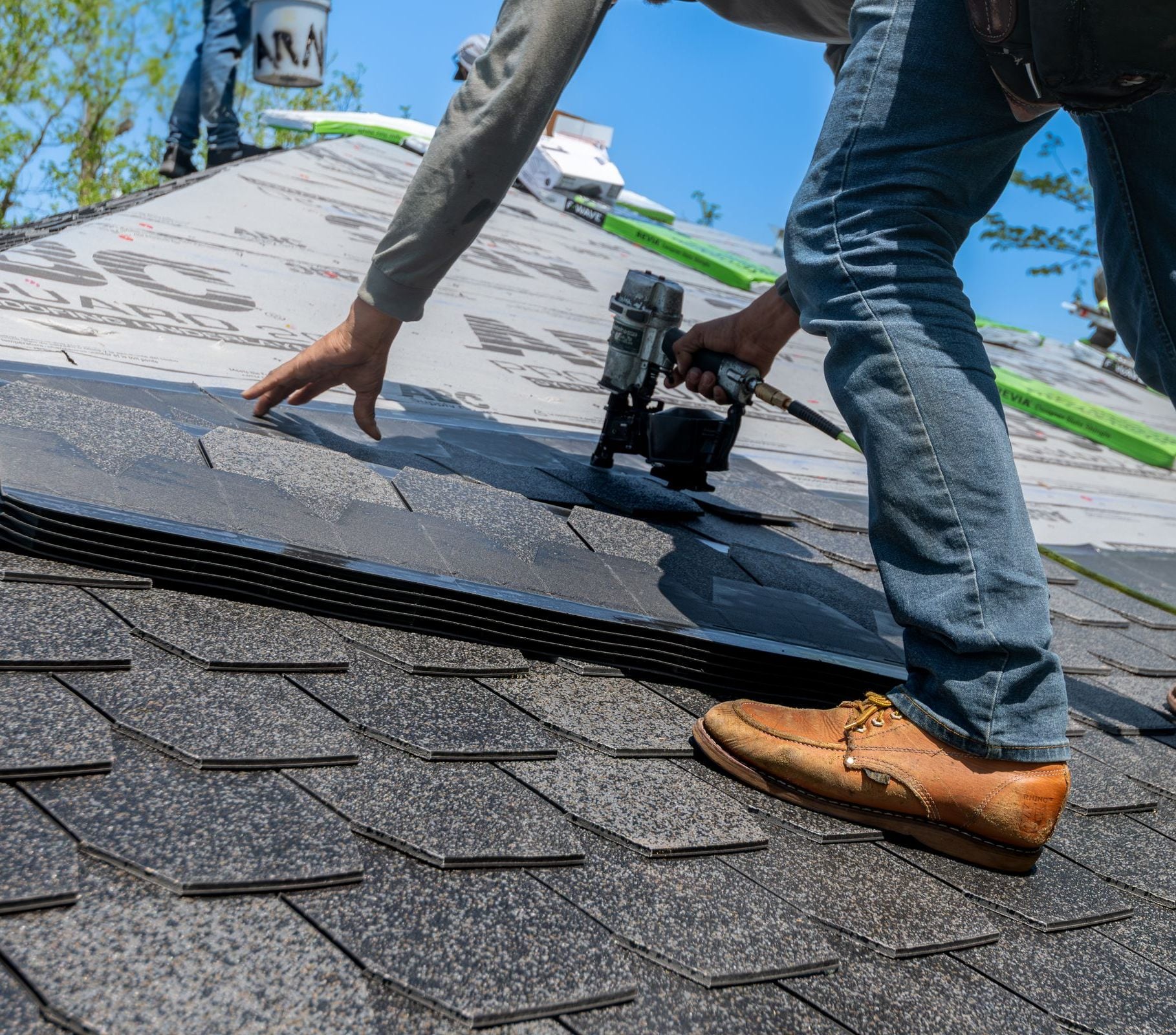 A roofing crew nailing shingles into place